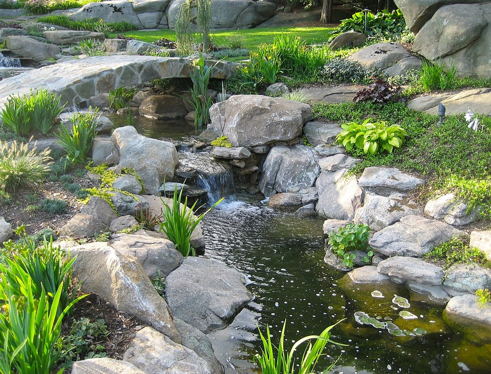 Modelo de jardín tradicional grande en ladera con fuente, exposición parcial al sol y adoquines de piedra natural