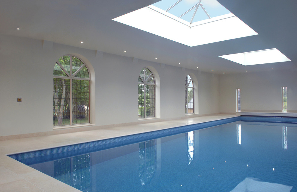 Design ideas for a mid-sized modern indoor rectangular pool in Other with a pool house and natural stone pavers.