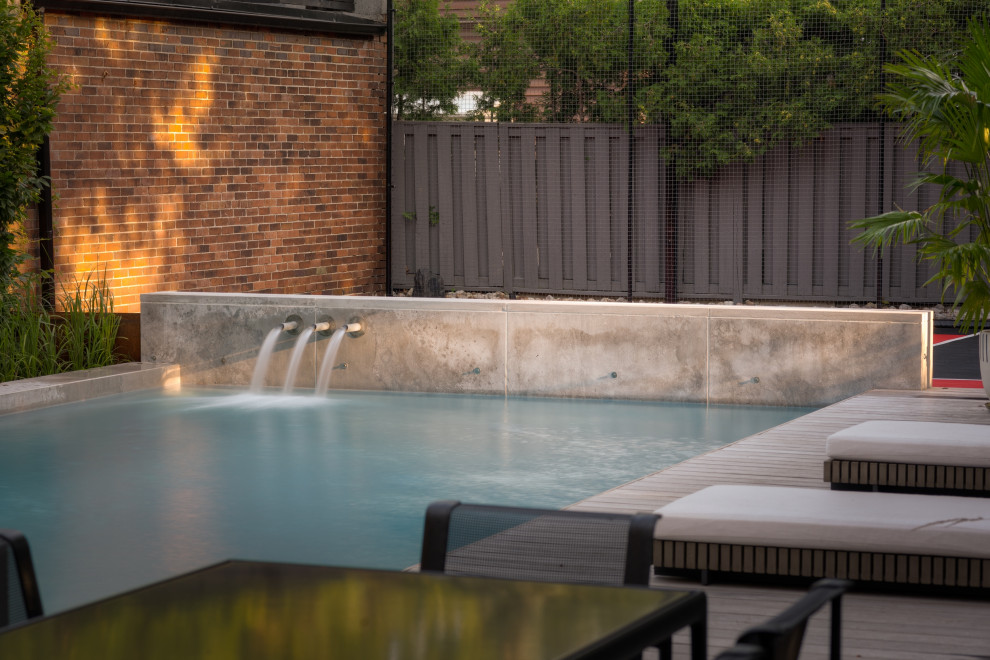 Ejemplo de piscina con fuente urbana de tamaño medio rectangular en patio trasero con entablado