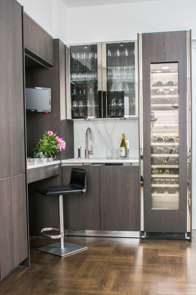 Photo of a small contemporary wet bar in New York with glass-front cabinets, white splashback and dark hardwood floors.