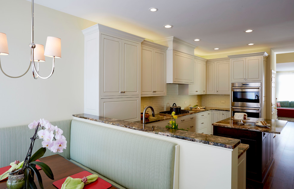 Enclosed kitchen - mid-sized transitional u-shaped medium tone wood floor enclosed kitchen idea in Chicago with a single-bowl sink, raised-panel cabinets, white cabinets, granite countertops, white backsplash, glass tile backsplash, stainless steel appliances and an island