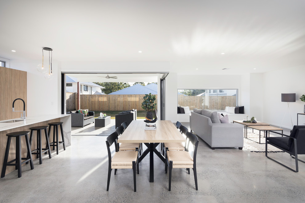 This is an example of a scandinavian open plan dining in Brisbane with white walls, concrete floors and brown floor.