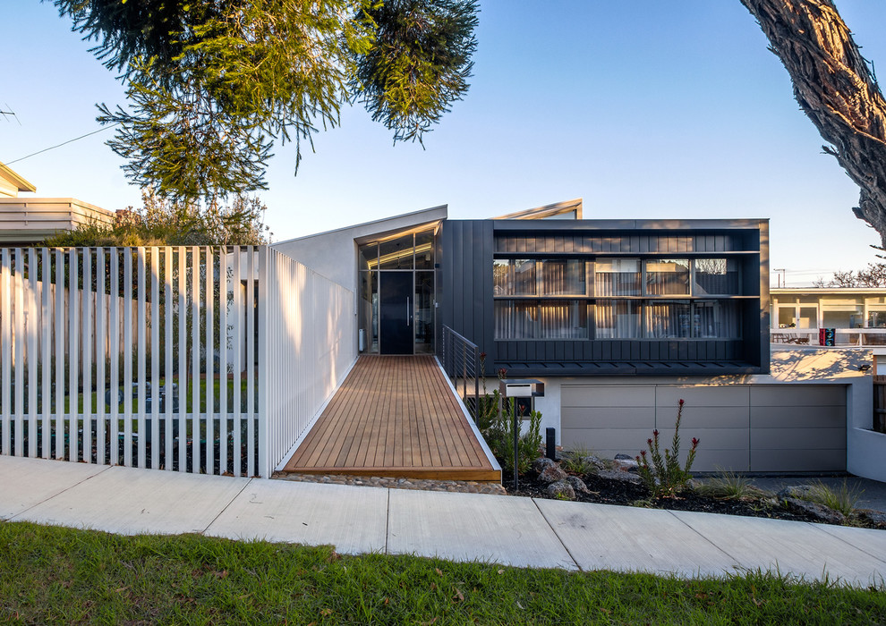 Photo of a large modern two-storey grey house exterior in Melbourne with metal siding, a flat roof and a metal roof.