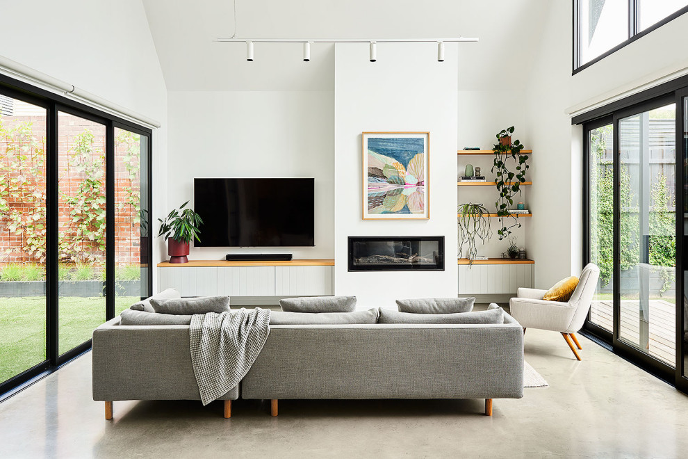 Imagen de sala de estar abierta y abovedada exótica de tamaño medio con paredes blancas, suelo de cemento, todas las chimeneas, marco de chimenea de yeso y suelo gris