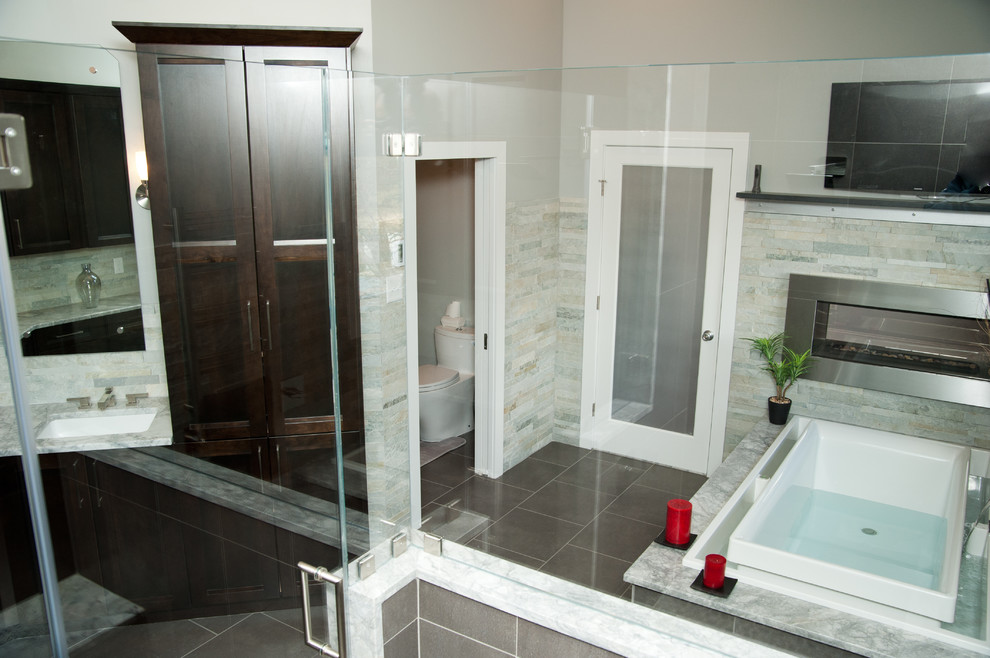 Inspiration for a large transitional master bathroom in New York with shaker cabinets, dark wood cabinets, a drop-in tub, a corner shower, a one-piece toilet, beige tile, gray tile, stone tile, grey walls, ceramic floors, an undermount sink and granite benchtops.