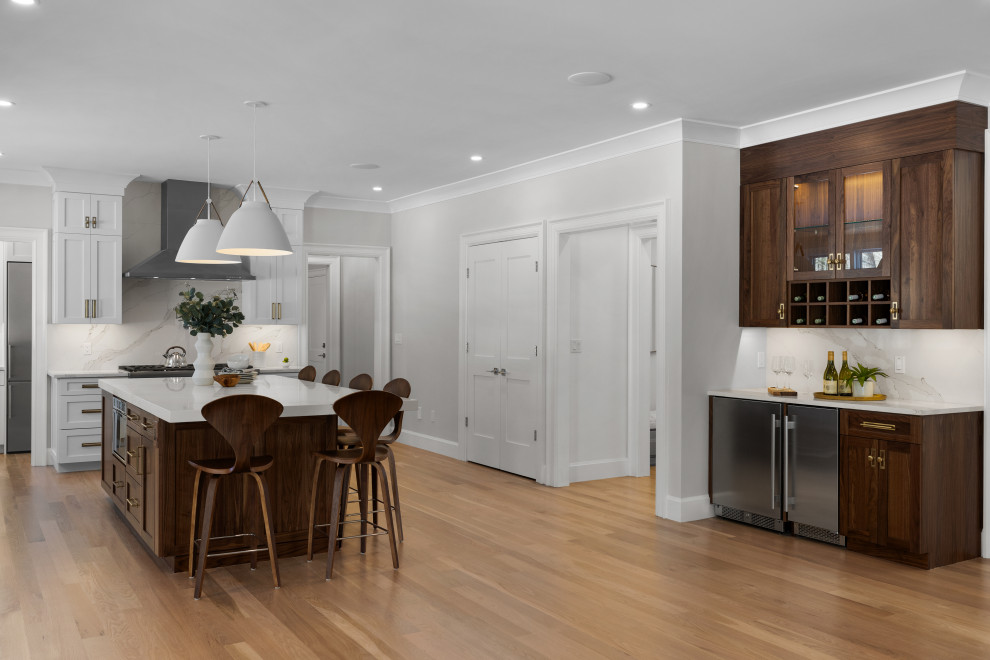 Inspiration for a large transitional light wood floor and brown floor open concept kitchen remodel in Boston with an undermount sink, shaker cabinets, medium tone wood cabinets, quartz countertops, white backsplash, quartz backsplash, stainless steel appliances, an island and white countertops