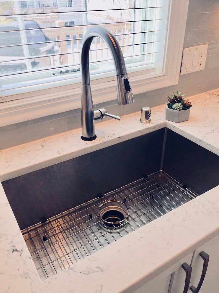 Mid-sized transitional light wood floor kitchen photo with an undermount sink, shaker cabinets, white cabinets, quartz countertops, blue backsplash, glass tile backsplash, stainless steel appliances and an island