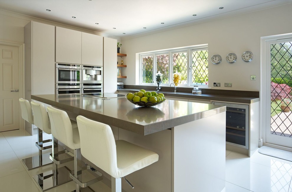 Design ideas for a large contemporary u-shaped eat-in kitchen in Hertfordshire with an undermount sink, flat-panel cabinets, grey cabinets, solid surface benchtops, stainless steel appliances, ceramic floors and a peninsula.