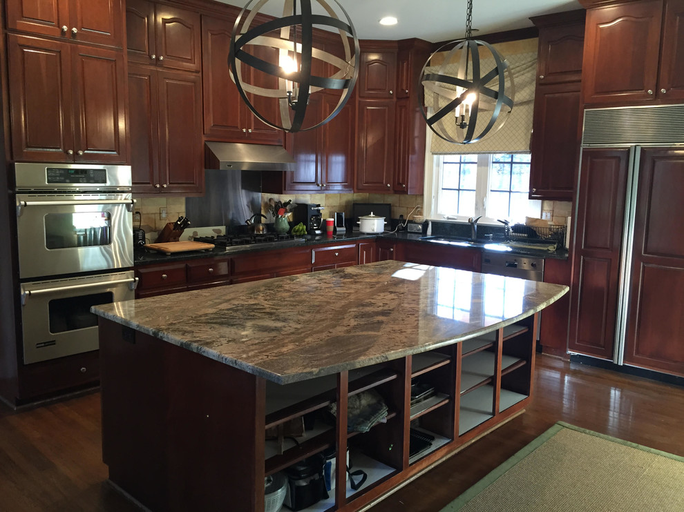 Eat-in kitchen - mid-sized transitional l-shaped medium tone wood floor and brown floor eat-in kitchen idea in Richmond with an undermount sink, raised-panel cabinets, dark wood cabinets, granite countertops, beige backsplash, stone tile backsplash, paneled appliances and an island