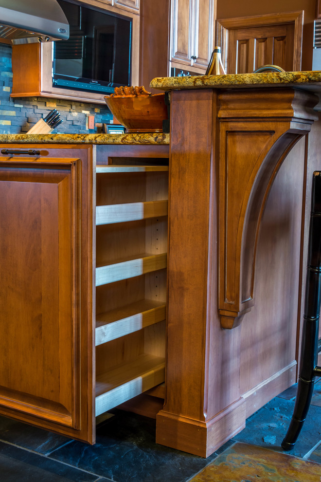 Small eclectic l-shaped slate floor open concept kitchen photo with raised-panel cabinets, light wood cabinets, granite countertops, black backsplash, stone tile backsplash, stainless steel appliances and an island