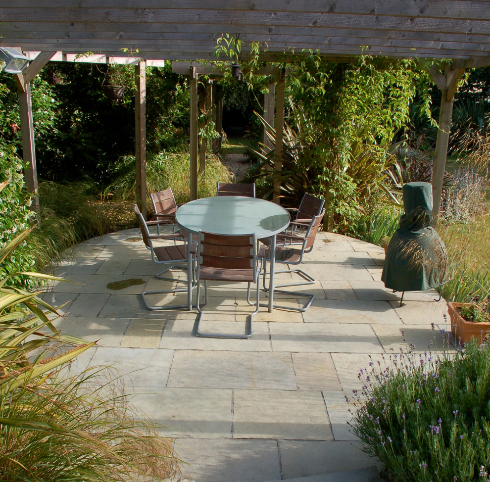 Design ideas for a large modern back xeriscape full sun pergola for summer in Dorset with natural stone paving.