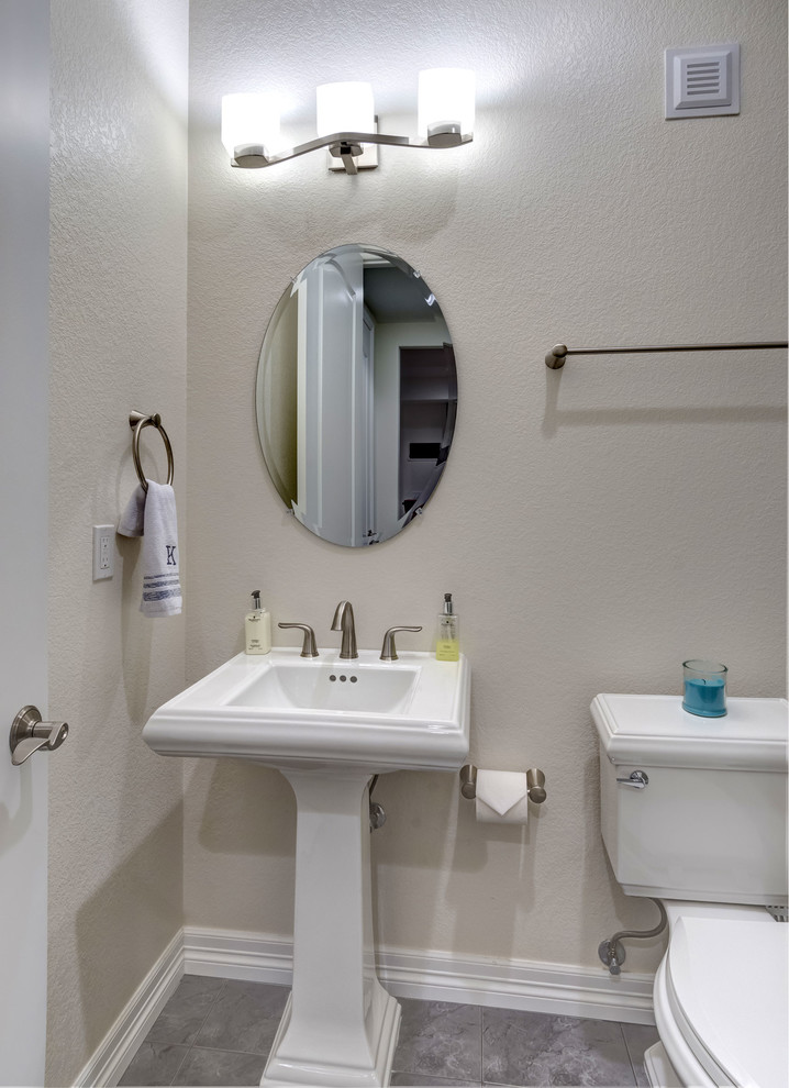 Photo of a mid-sized transitional powder room in Denver with a two-piece toilet, beige walls, slate floors, a pedestal sink and grey floor.