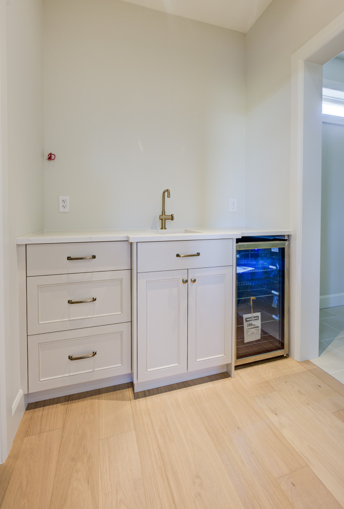 Example of a mid-sized transitional single-wall light wood floor open concept kitchen design in Toronto with an undermount sink, shaker cabinets, white cabinets, quartz countertops, stainless steel appliances, an island and white countertops