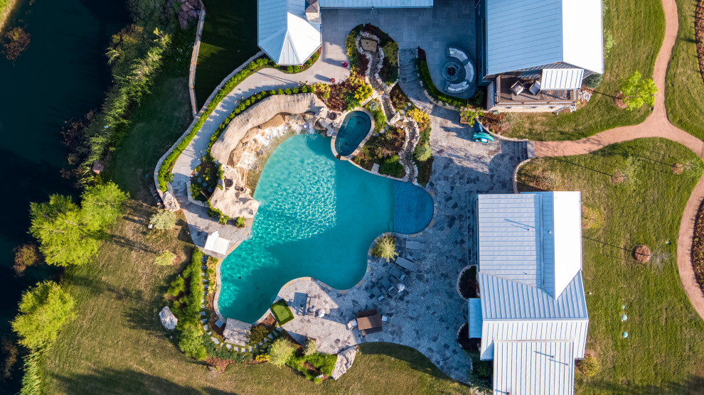 Inspiration for an expansive country backyard custom-shaped natural pool in Oklahoma City with with a pool and natural stone pavers.