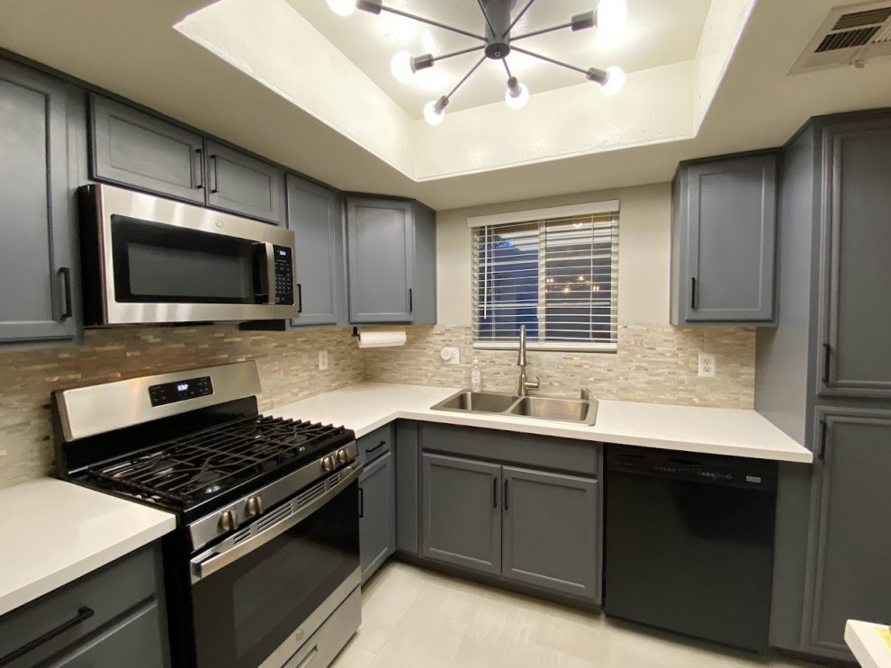 Photo of a small traditional l-shaped open plan kitchen in Las Vegas with a built-in sink, recessed-panel cabinets, grey cabinets, engineered stone countertops, beige splashback, mosaic tiled splashback, black appliances, ceramic flooring, no island, white floors, white worktops and a drop ceiling.