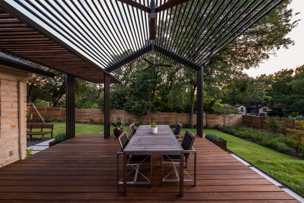 This is an example of a contemporary ground level deck in Austin with a pergola.