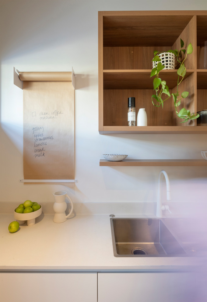 Large contemporary galley kitchen in Brisbane with an undermount sink, quartz benchtops, matchstick tile splashback, panelled appliances, concrete floors, with island, grey floor and white benchtop.