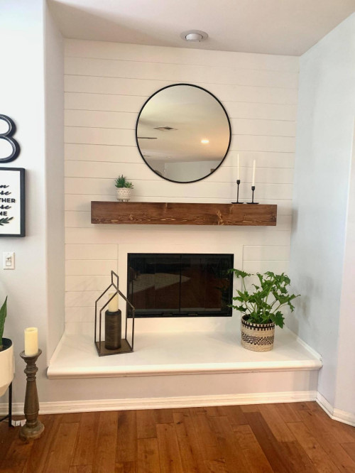 This fireplace is adorned with shiplap. Installed is also a custom stained pine mantle. A mid-sized modern laminate floor, brown floor and shiplap wall living room remodel in Orange County with white walls, a standard fireplace,  and a tv stand