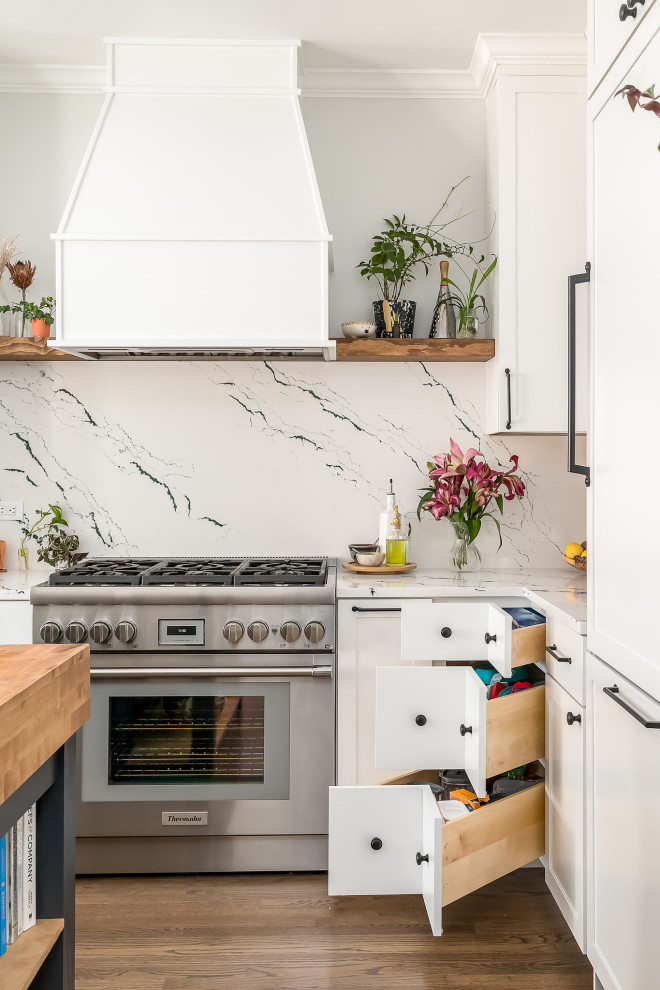 Mid-sized transitional l-shaped medium tone wood floor and brown floor kitchen photo in Chicago with an undermount sink, shaker cabinets, white cabinets, quartz countertops, white backsplash, quartz backsplash, paneled appliances, an island and white countertops