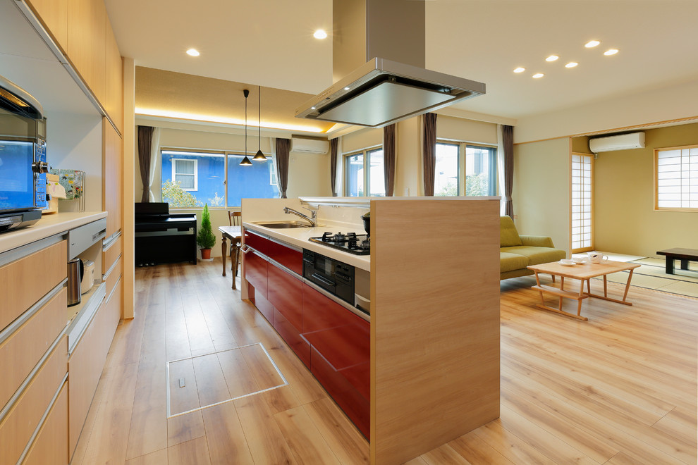 Modern single-wall open plan kitchen in Tokyo with a single-bowl sink, flat-panel cabinets, red cabinets, white splashback, light hardwood floors, with island and beige floor.