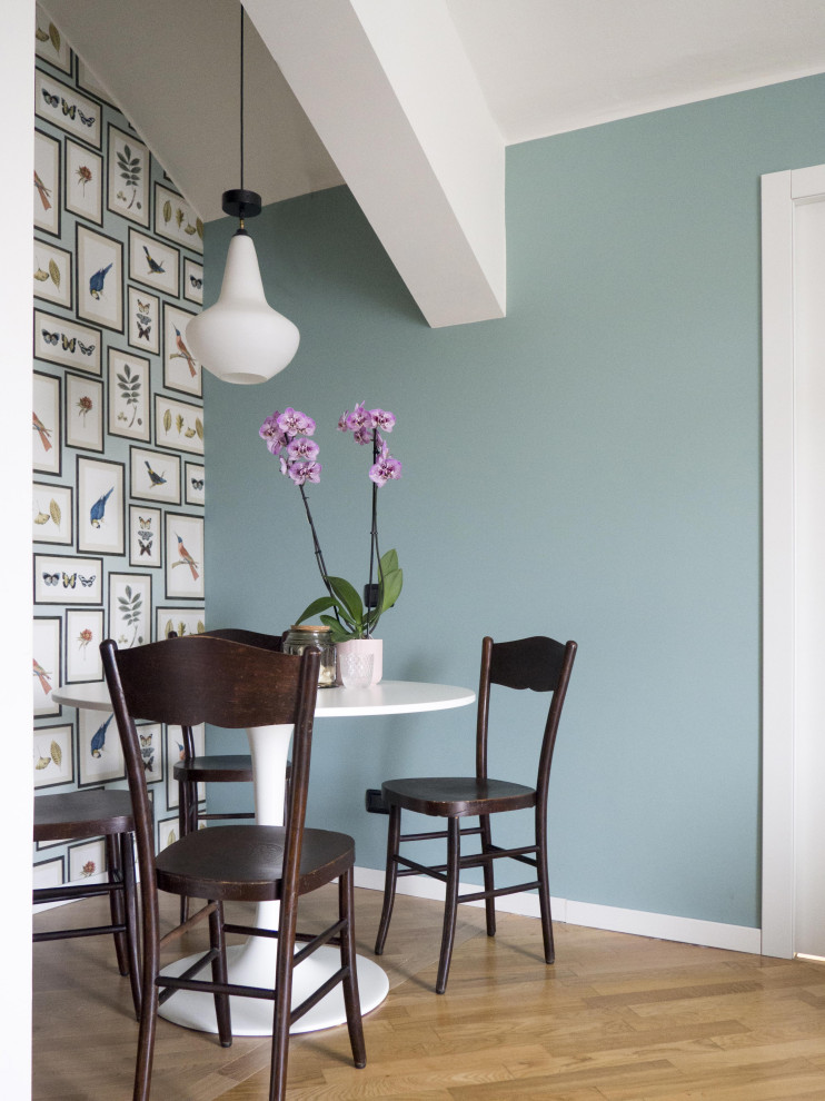 This is an example of a small eclectic dining room in Milan with banquette seating, green walls and painted wood flooring.