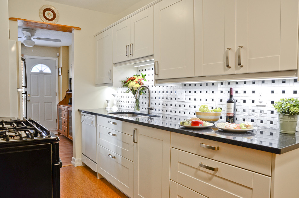 Example of a small transitional galley cork floor kitchen design in Ottawa with an undermount sink, shaker cabinets, white cabinets, quartz countertops, white backsplash, porcelain backsplash and black appliances