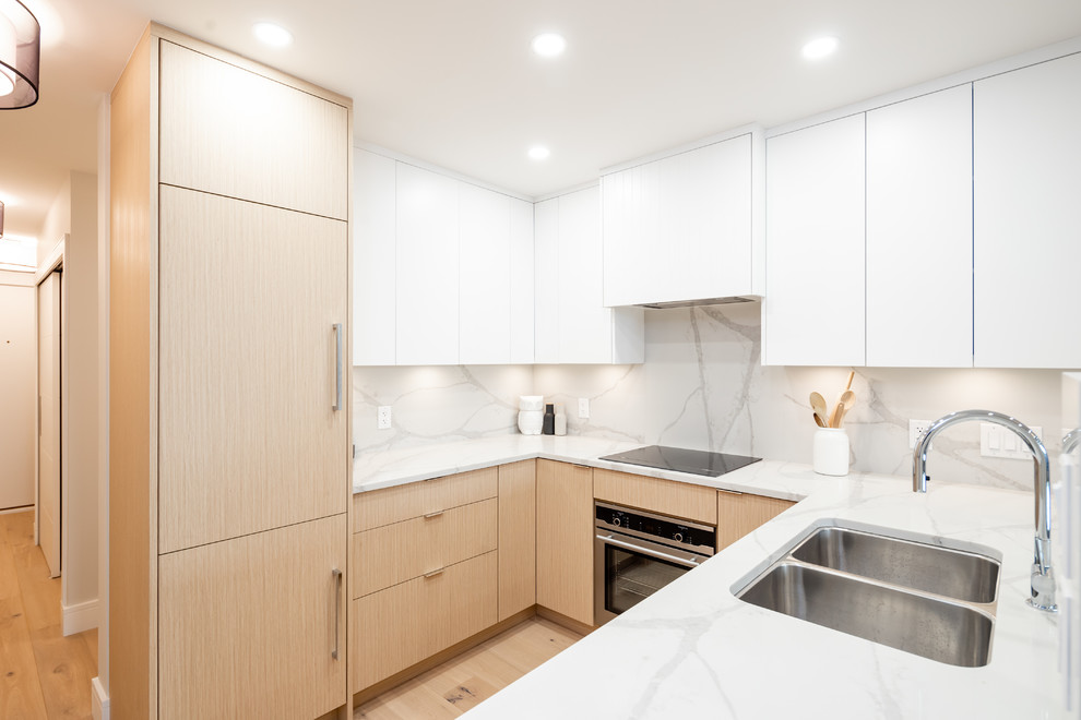 Design ideas for a small contemporary u-shaped eat-in kitchen in Vancouver with an undermount sink, flat-panel cabinets, light wood cabinets, quartz benchtops, white splashback, stone slab splashback, panelled appliances, light hardwood floors, a peninsula and white benchtop.