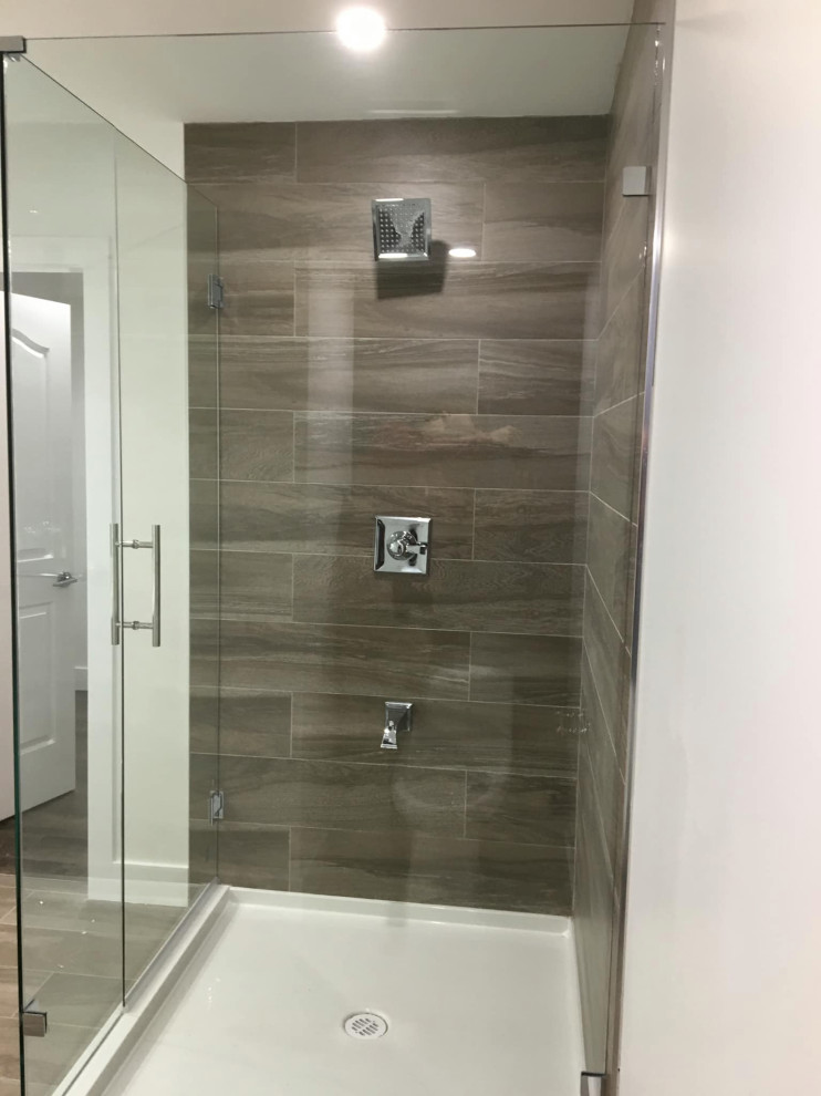 Photo of a medium sized modern ensuite bathroom in Newark with freestanding cabinets, white cabinets, a corner bath, a built-in shower, a one-piece toilet, white tiles, limestone tiles, black walls, ceramic flooring, a submerged sink, brown floors, a hinged door, grey worktops, an enclosed toilet, a single sink, a freestanding vanity unit, a timber clad ceiling and wood walls.