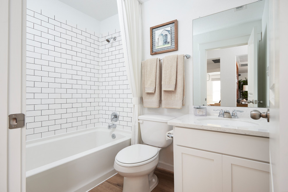 Inspiration for a mid-sized contemporary kids bathroom in Other with recessed-panel cabinets, beige cabinets, a shower/bathtub combo, white tile, subway tile, white walls, medium hardwood floors, an undermount sink, marble benchtops, brown floor, a shower curtain, beige benchtops and a single vanity.