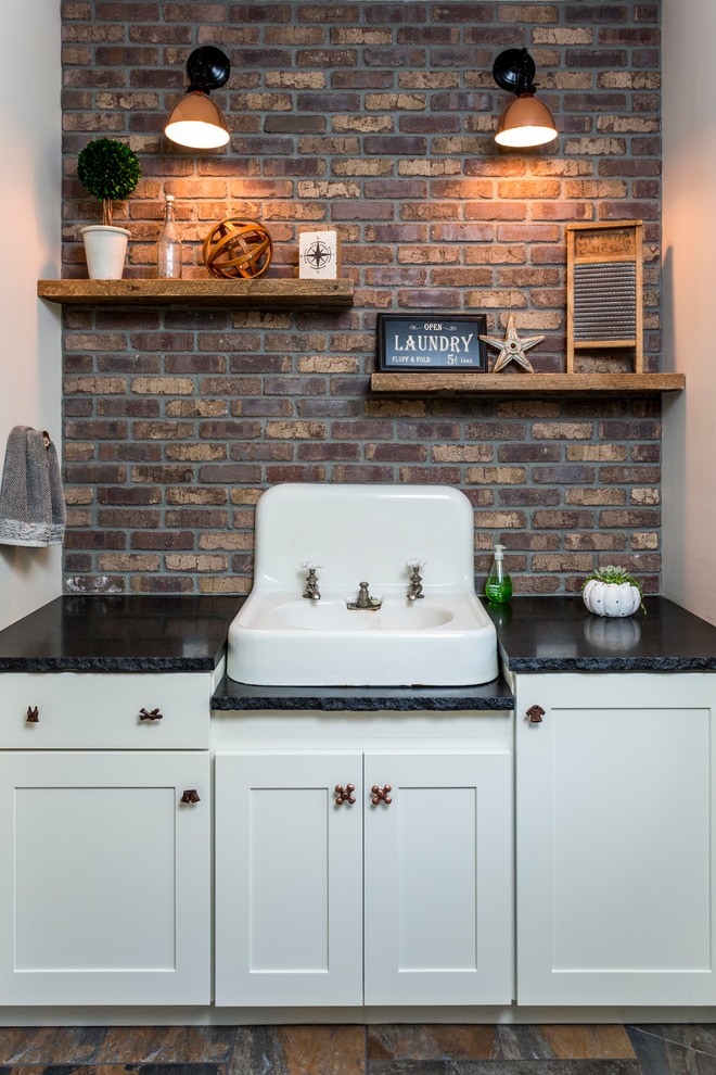 This is an example of a mid-sized industrial laundry room in Portland Maine with shaker cabinets, white cabinets, granite benchtops, slate floors, multi-coloured walls and a drop-in sink.