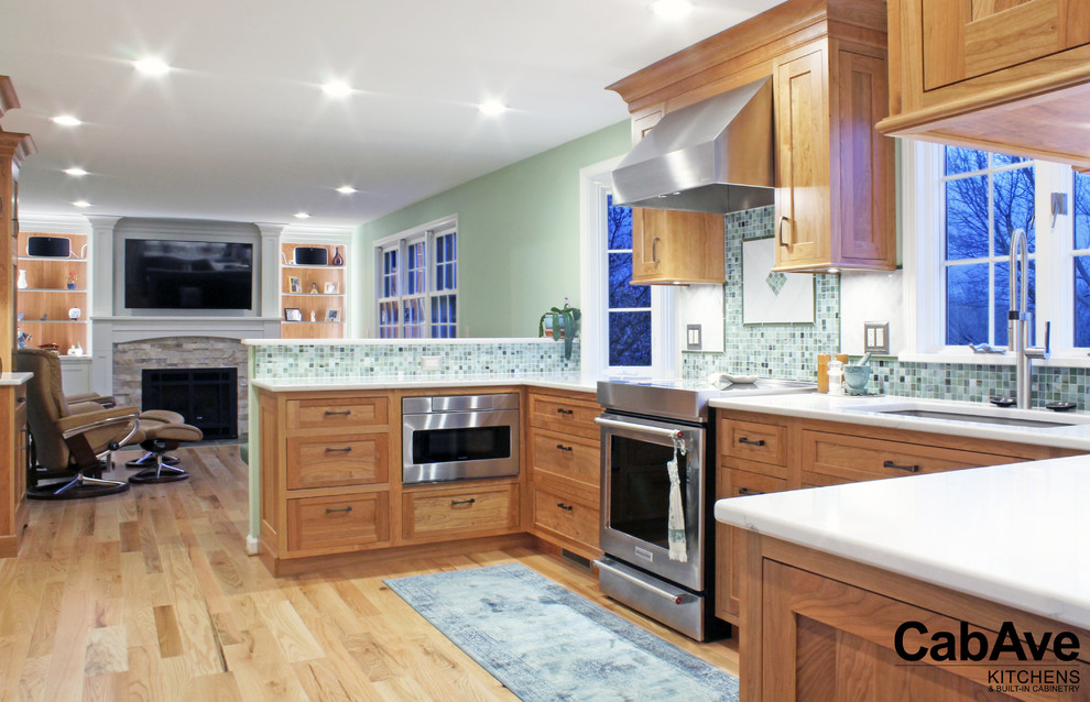 Example of a large transitional u-shaped light wood floor and beige floor open concept kitchen design with an undermount sink, recessed-panel cabinets, light wood cabinets, quartz countertops, green backsplash, mosaic tile backsplash, stainless steel appliances and a peninsula