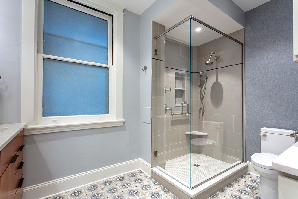 This is an example of a small transitional master bathroom in Other with flat-panel cabinets, medium wood cabinets, a corner shower, a two-piece toilet, beige tile, porcelain tile, blue walls, porcelain floors, an undermount sink, engineered quartz benchtops, multi-coloured floor, a hinged shower door and white benchtops.