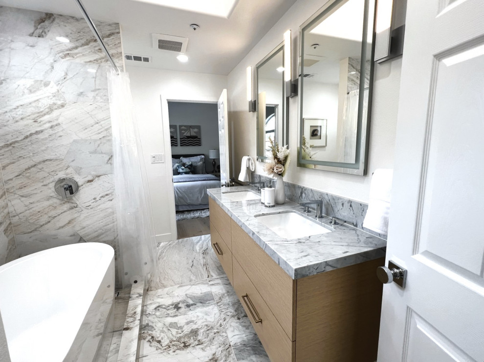 Idée de décoration pour une petite salle de bain design en bois clair avec un placard à porte plane, une baignoire encastrée, WC à poser, un carrelage gris, du carrelage en marbre, un mur blanc, un sol en marbre, un lavabo encastré, un plan de toilette en marbre, un sol gris, une cabine de douche avec un rideau, un plan de toilette blanc, meuble double vasque et meuble-lavabo suspendu.