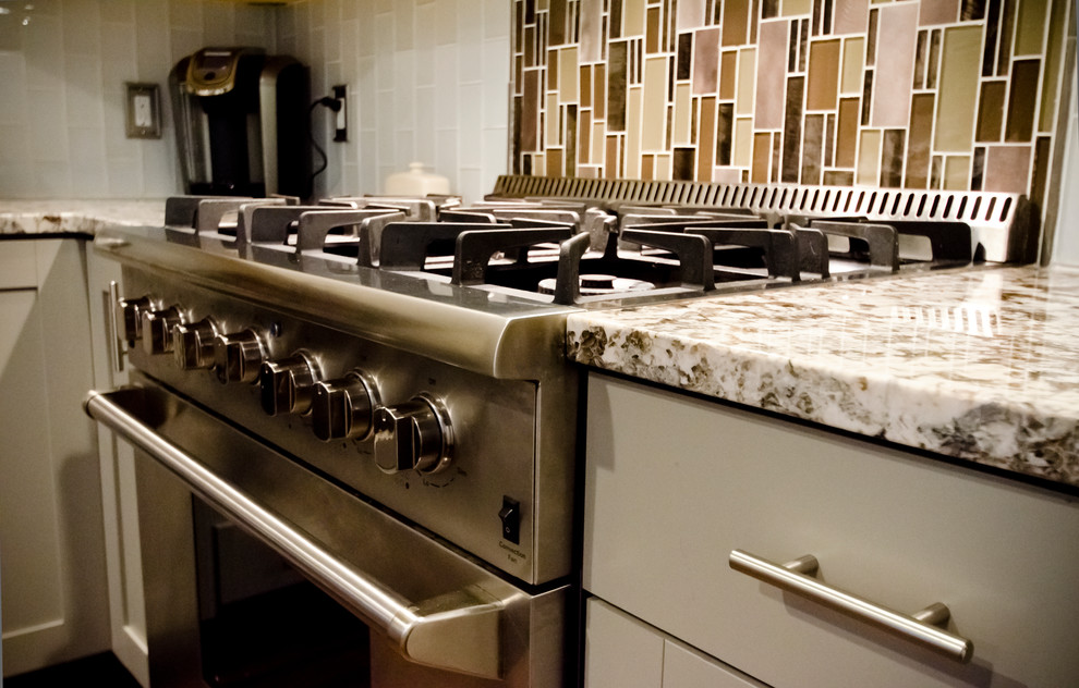 Mid-sized trendy l-shaped vinyl floor and brown floor eat-in kitchen photo in Chicago with a farmhouse sink, shaker cabinets, gray cabinets, granite countertops, white backsplash, glass tile backsplash, stainless steel appliances and an island