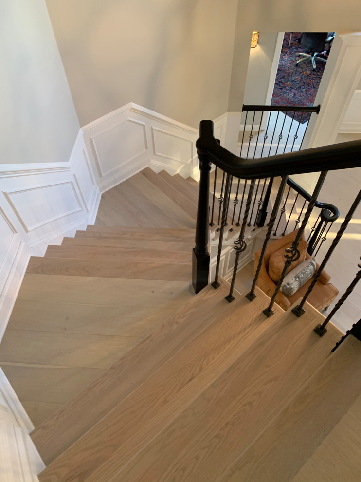 Imagen de escalera curva clásica renovada grande con escalones de madera, contrahuellas de madera y barandilla de madera
