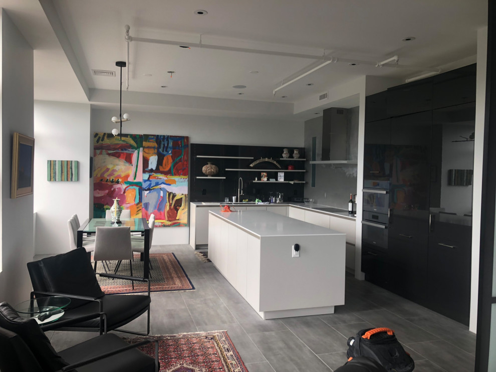Photo of a mid-sized contemporary l-shaped eat-in kitchen in Boston with an undermount sink, flat-panel cabinets, black cabinets, tile benchtops, panelled appliances, ceramic floors, with island, grey floor, white benchtop and coffered.