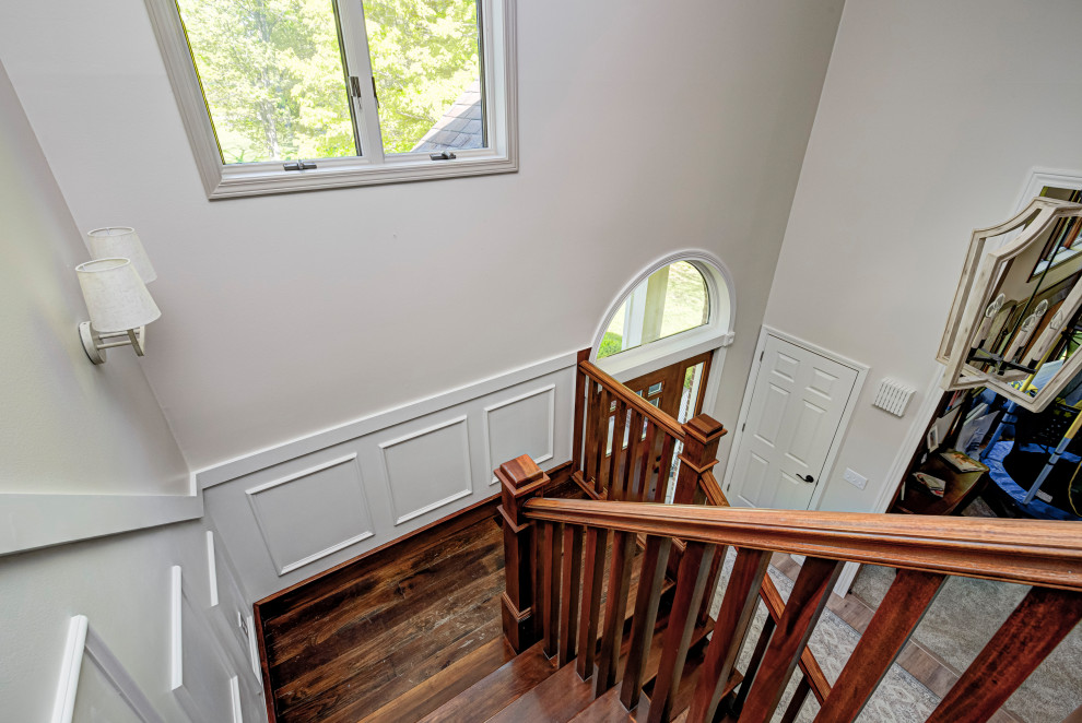 На фото: п-образная деревянная лестница среднего размера в классическом стиле с деревянными ступенями, деревянными перилами и панелями на стенах