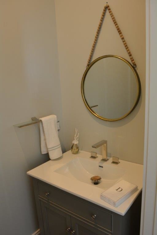 This is an example of a small beach style powder room in Other with furniture-like cabinets, grey cabinets, a one-piece toilet, grey walls and an integrated sink.