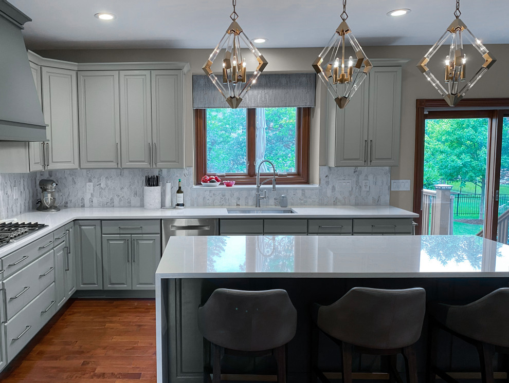 Photo of a medium sized traditional l-shaped kitchen/diner in Chicago with a submerged sink, raised-panel cabinets, grey cabinets, engineered stone countertops, white splashback, marble splashback, stainless steel appliances, dark hardwood flooring, an island and white worktops.