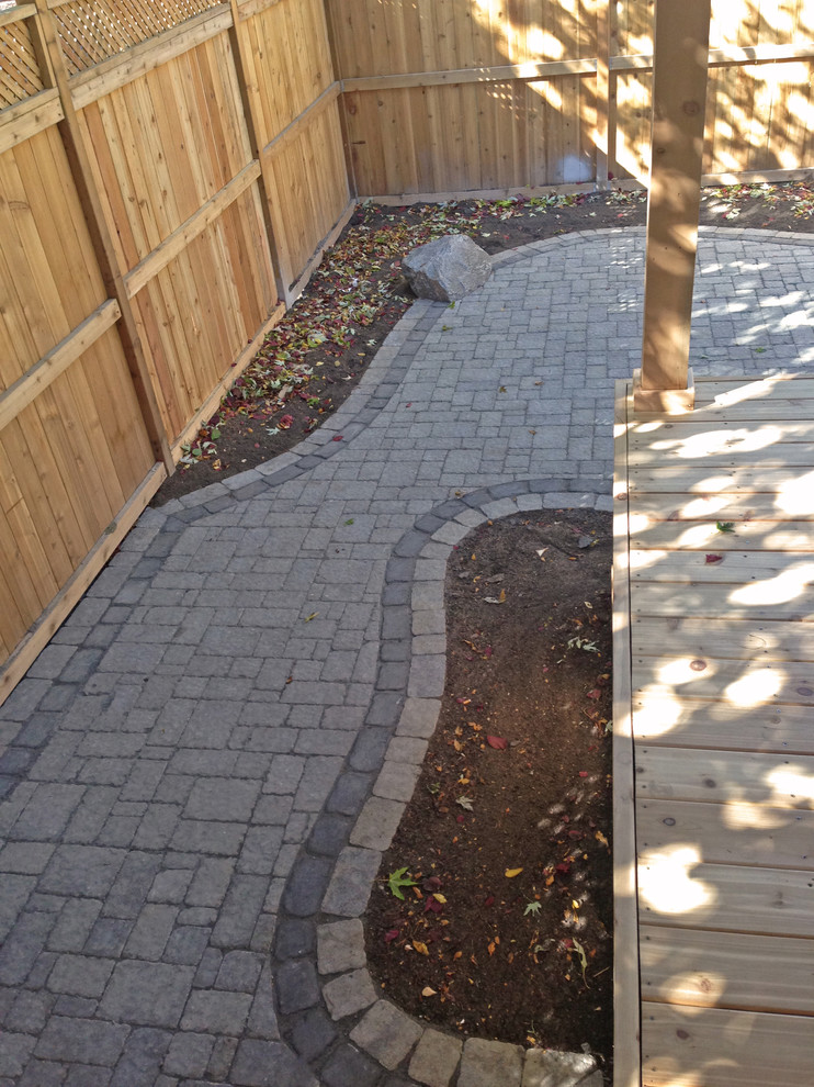 Large minimalist backyard deck photo in Ottawa with a roof extension