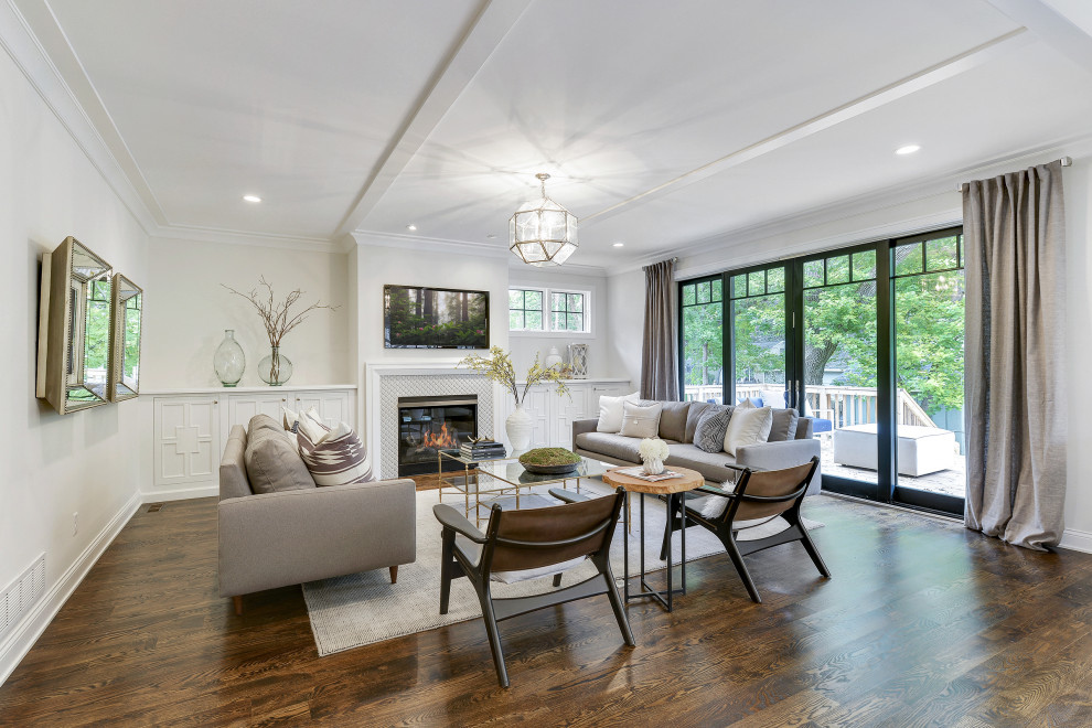 Example of a large classic formal and open concept dark wood floor, brown floor, tray ceiling and wainscoting living room design in Minneapolis with white walls, a standard fireplace, a tile fireplace and a wall-mounted tv