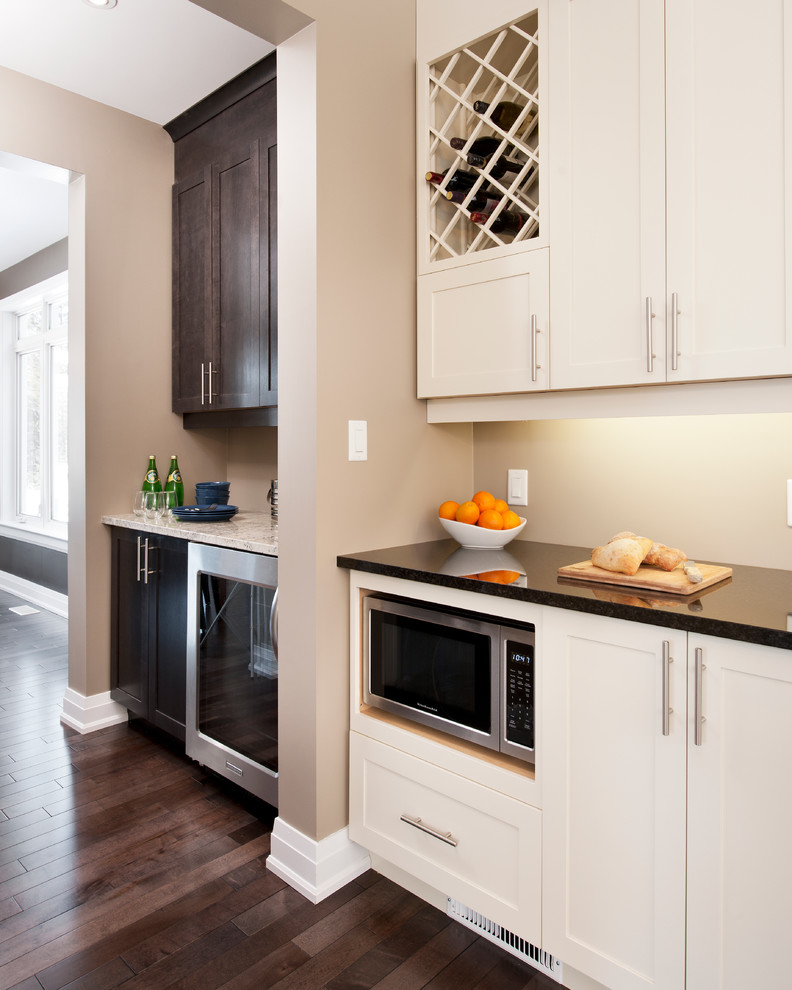 Large traditional l-shaped open plan kitchen in Ottawa with an undermount sink, shaker cabinets, white cabinets, solid surface benchtops, stainless steel appliances, dark hardwood floors and with island.