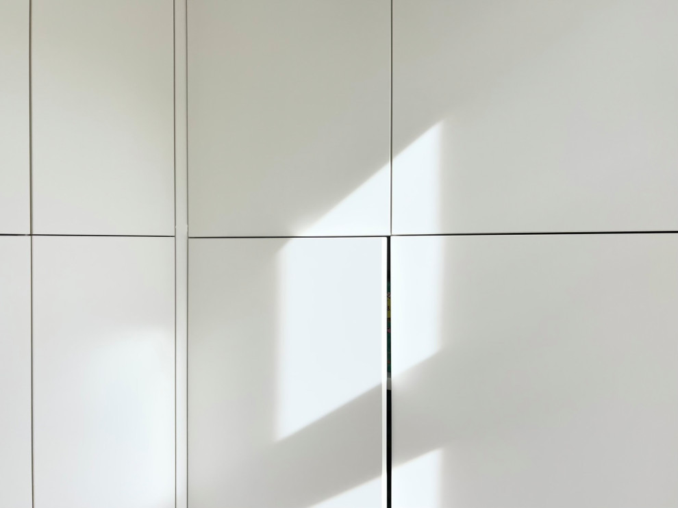 Kleiner Moderner Hauswirtschaftsraum in L-Form mit Waschmaschinenschrank, flächenbündigen Schrankfronten, weißen Schränken, weißer Wandfarbe, hellem Holzboden und braunem Boden in Berlin