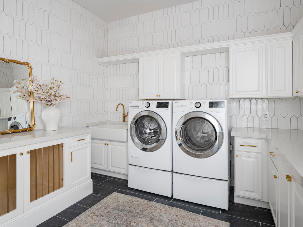 Large transitional l-shaped dedicated laundry room in Phoenix with an undermount sink, raised-panel cabinets, white cabinets, quartz benchtops, white splashback, ceramic splashback, white walls, limestone floors, a side-by-side washer and dryer, black floor and white benchtop.