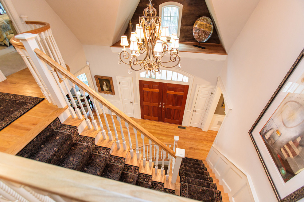 Photo of an expansive traditional carpeted curved staircase in Boston with carpet risers and wood railing.