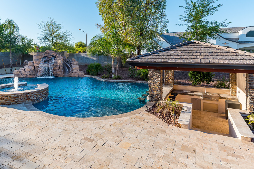 Photo of an expansive traditional backyard custom-shaped natural pool in Phoenix with a water slide and natural stone pavers.