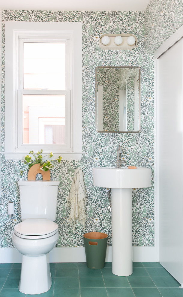 Modern inredning av ett vit vitt toalett, med öppna hyllor, vita skåp, en toalettstol med separat cisternkåpa, flerfärgade väggar, ett piedestal handfat och grönt golv