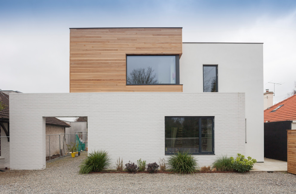 Mid-sized contemporary two-storey brick white house exterior in Dublin with a flat roof and a green roof.