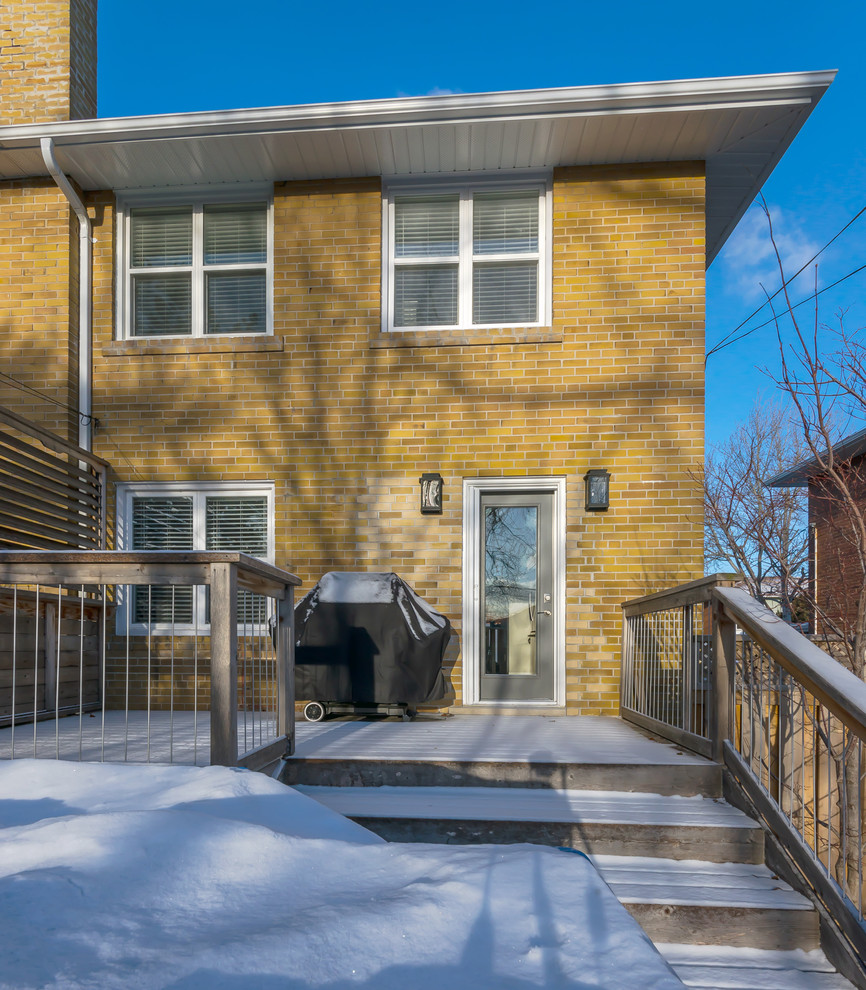 Small transitional yellow two-story brick exterior home idea in Toronto with a hip roof