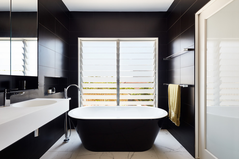 Contemporary master bathroom in Sydney with a freestanding tub, black tile, black walls, an integrated sink and white floor.